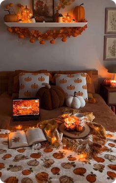 a bed with pumpkins and candles on it in front of an open laptop computer