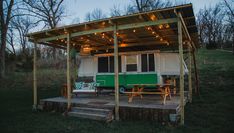 a green and white camper parked under a covered area with lights on the roof