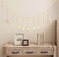 a wooden table topped with a framed photo next to a string of moon phases hanging from the ceiling