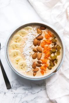 a bowl of oatmeal topped with bananas, carrots and almonds