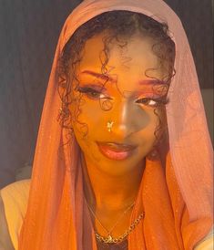 a woman wearing an orange veil and gold jewelry is posing for the camera with her eyes closed