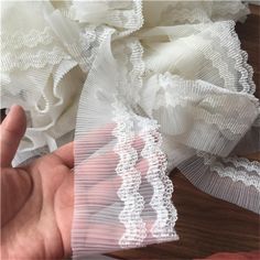 someone is holding some white lace on their left hand and it looks like they are making something out of fabric