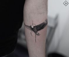 a black and white photo of a bird tattoo on the left upper half of the arm