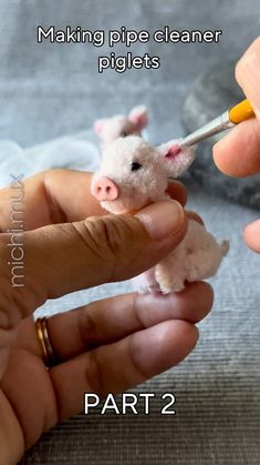 a hand holding a tiny pig with a needle in it's mouth and the caption making pipe cleaner pluglets part 2