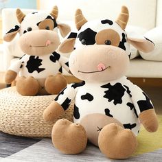 two stuffed cows sitting next to each other on a rug