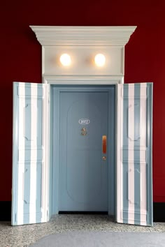 an open door with two lights on the top and bottom, in front of a red wall