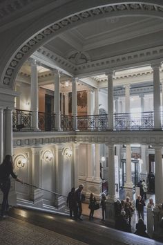 people are standing in an ornate building with columns and balconies on the second floor