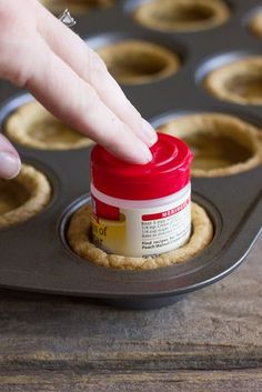 a hand reaching into a cupcake tin