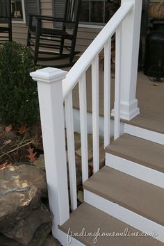 a porch with white railings and chairs on the front steps, next to a rock garden