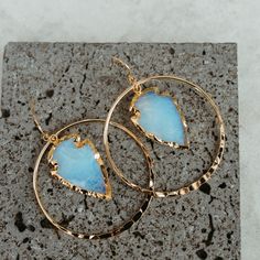 Opalite is a purity stone that stimulates joy and positive vibrations. The powder blue white color feels angelic. These handmade, gold hammered hoops are unique and make you feel like you own every room you step into. 2" hammered gold plated hoops Opalite arrowheads electroplated in 14k gold Drop length 2.5" Weight: 1/4 oz Handmade in Arizona Because all crystals & gemstones are unique they may vary in shape, size or appearance. Gift Hoop Earrings With Natural Stones, Spiritual Hoop Jewelry As Gift, Opal Hoop Earrings As A Gift, Everyday Nickel Free Moonstone Jewelry, Round Moonstone Hoop Earrings As A Gift, Celestial Hoop Jewelry As Gift, Round Halo Hoop Earrings As Gift, Moonstone Hoop Earrings Gift, Hoop Jewelry With Natural Stones For Gift