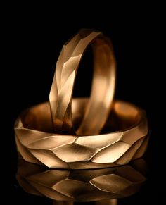 two gold wedding bands sitting on top of each other