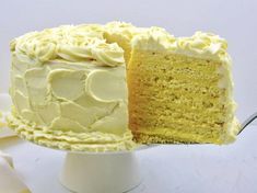 a white cake with yellow frosting and a slice taken out of it's side