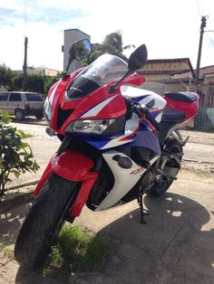 a red, white and blue motorcycle is parked on the sidewalk