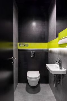 a bathroom with a toilet, sink and mirror in it's stall area at night