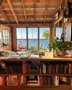 a living room filled with lots of books and furniture next to a large open window