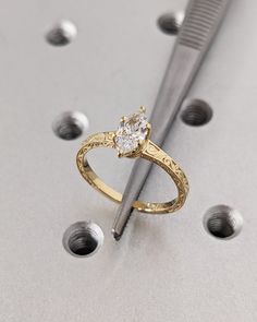 a diamond ring sitting on top of a table next to a metal pen and screwdriver