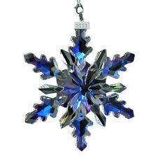 a blue snowflake ornament hanging from a silver chain on a white background