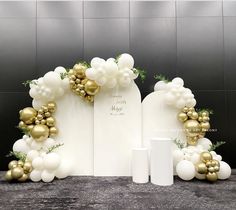 white and gold balloon arch with greenery on the top, next to two mugs