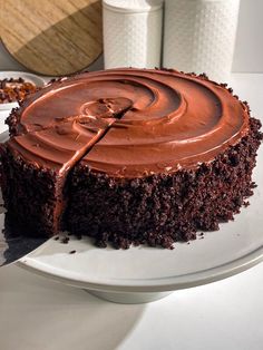 a piece of chocolate cake on a plate with a knife in it's middle