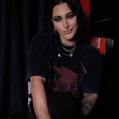 a woman with black hair and piercings sitting in front of a piano