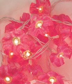 pink flowers with lights attached to them on a white surface