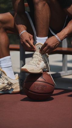 a man tying his shoe on top of a basketball