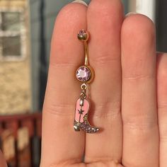 a person holding up a pink and gold charm with a letter on it's side