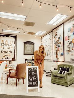 a woman standing next to a sign in a room filled with furniture and signs on the wall