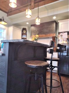 a kitchen with two stools and an island in the middle, surrounded by lights