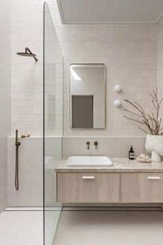 a white bathroom with two sinks and a large mirror on the wall next to it