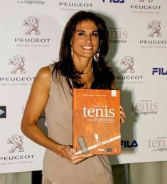 a woman holding up a book in front of a white wall with the words tennis on it