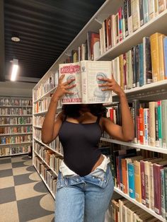 a woman is holding up a book in front of her face while standing in the library