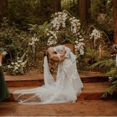 a bride and groom kissing in front of an outdoor wedding ceremony area with white flowers