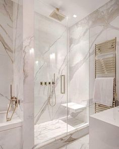 a bathroom with white marble walls and flooring, along with a walk in shower