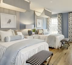 two beds in a room with blue walls and white bedding, one has a striped pillow on the headboard