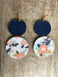 two round earrings with floral designs on them sitting on top of a wooden table next to a pair of scissors