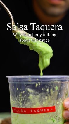 a person holding a spoon over a cup filled with green liquid and something in it