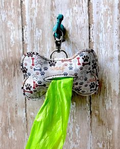 a dog bone shaped keychain hanging on a wooden door with a green umbrella