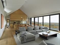 a living room filled with lots of furniture and large windows overlooking the mountains in the distance