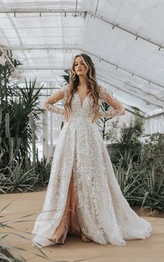 a woman in a white wedding dress with long sleeves and an open back standing on a patio