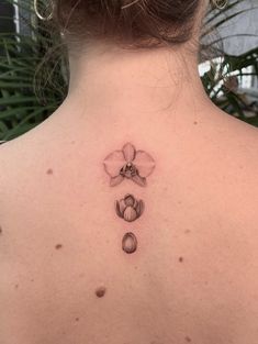 the back of a woman's neck with a flower tattoo on it