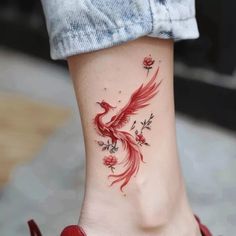 a woman's foot with a red bird tattoo on it