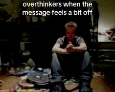 a man sitting on the floor in front of a pile of junk and other items