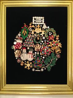 an embroidered christmas ornament in a gold frame on a black background with white trimmings