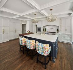 a large kitchen with white cabinets and an island in the middle, surrounded by bar stools