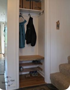 an open closet with two coats hanging on the wall and shoes sitting on the floor