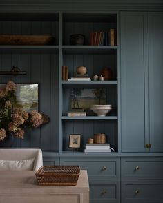 a living room with blue bookcases and flowers on the shelf next to it