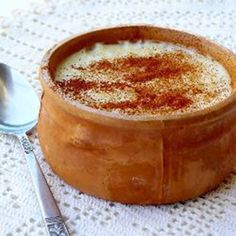 a wooden bowl filled with food on top of a white table cloth next to a spoon