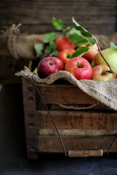 a wooden crate filled with lots of different types of apples on top of a table