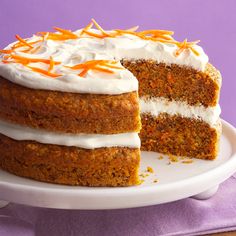 a carrot cake with white frosting and orange sprinkles on a plate